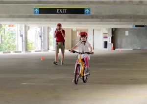 Child Riding Bike with Helmet in Empty Parking Garage