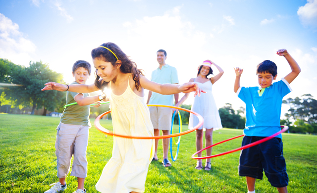 Children playing hula hoop in a grassy field